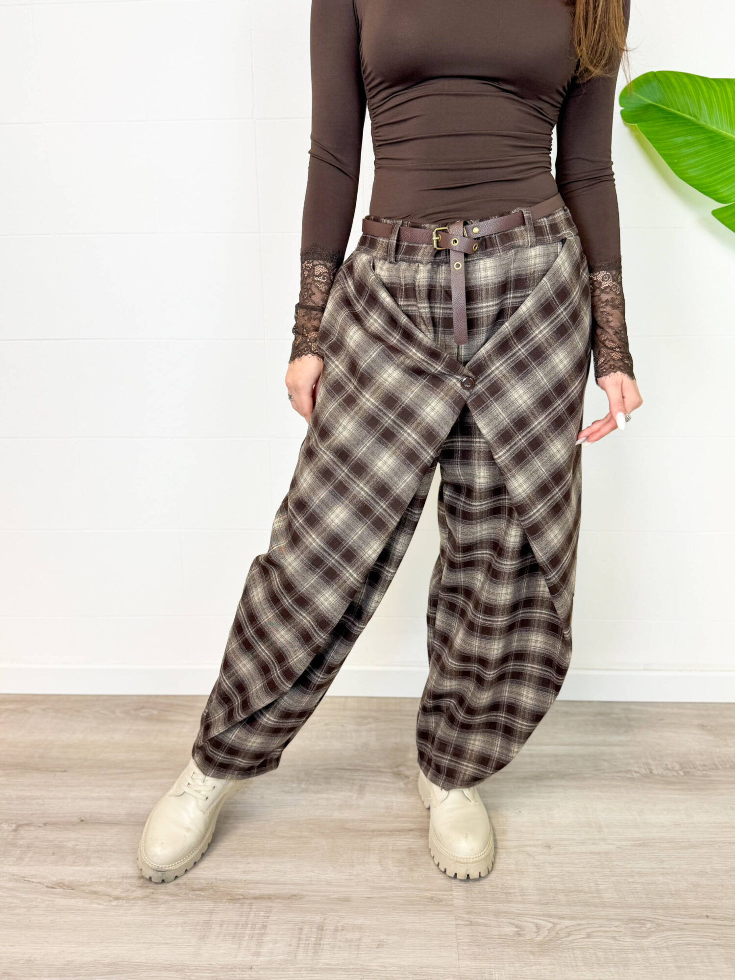 Aggiungi un tacco di stile audace e contemporaneo al tuo guardaroba con questi pantaloni cargo baggy a quadri. Caratterizzati da un motivo tartan nei toni caldi del marrone, nero e grigio, offrono il perfetto connubio tra estetica vintage Y2K, atmosfera grunge e massimo comfort quotidiano. Design e Vestibilità: Taglio ampio e morbido (baggy/balloon) con caviglie leggermente arricciate/regolabili per creare un volume moderno e rilassato. Dettagli Funzionali: Chiusura frontale con zip e bottone, passanti per cintura e pratiche tasche laterali stile cargo per un look urbano e pratico. Versatilità di Stile: Perfetti da abbinare con anfibi o sneaker spesse, top aderenti a manica lunga o maglioni oversize per un outfit da giorno grintoso ed eclettico.
