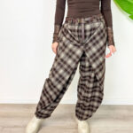 Aggiungi un tacco di stile audace e contemporaneo al tuo guardaroba con questi pantaloni cargo baggy a quadri. Caratterizzati da un motivo tartan nei toni caldi del marrone, nero e grigio, offrono il perfetto connubio tra estetica vintage Y2K, atmosfera grunge e massimo comfort quotidiano. Design e Vestibilità: Taglio ampio e morbido (baggy/balloon) con caviglie leggermente arricciate/regolabili per creare un volume moderno e rilassato. Dettagli Funzionali: Chiusura frontale con zip e bottone, passanti per cintura e pratiche tasche laterali stile cargo per un look urbano e pratico. Versatilità di Stile: Perfetti da abbinare con anfibi o sneaker spesse, top aderenti a manica lunga o maglioni oversize per un outfit da giorno grintoso ed eclettico.