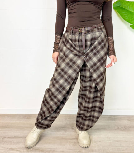 Aggiungi un tacco di stile audace e contemporaneo al tuo guardaroba con questi pantaloni cargo baggy a quadri. Caratterizzati da un motivo tartan nei toni caldi del marrone, nero e grigio, offrono il perfetto connubio tra estetica vintage Y2K, atmosfera grunge e massimo comfort quotidiano. Design e Vestibilità: Taglio ampio e morbido (baggy/balloon) con caviglie leggermente arricciate/regolabili per creare un volume moderno e rilassato. Dettagli Funzionali: Chiusura frontale con zip e bottone, passanti per cintura e pratiche tasche laterali stile cargo per un look urbano e pratico. Versatilità di Stile: Perfetti da abbinare con anfibi o sneaker spesse, top aderenti a manica lunga o maglioni oversize per un outfit da giorno grintoso ed eclettico.