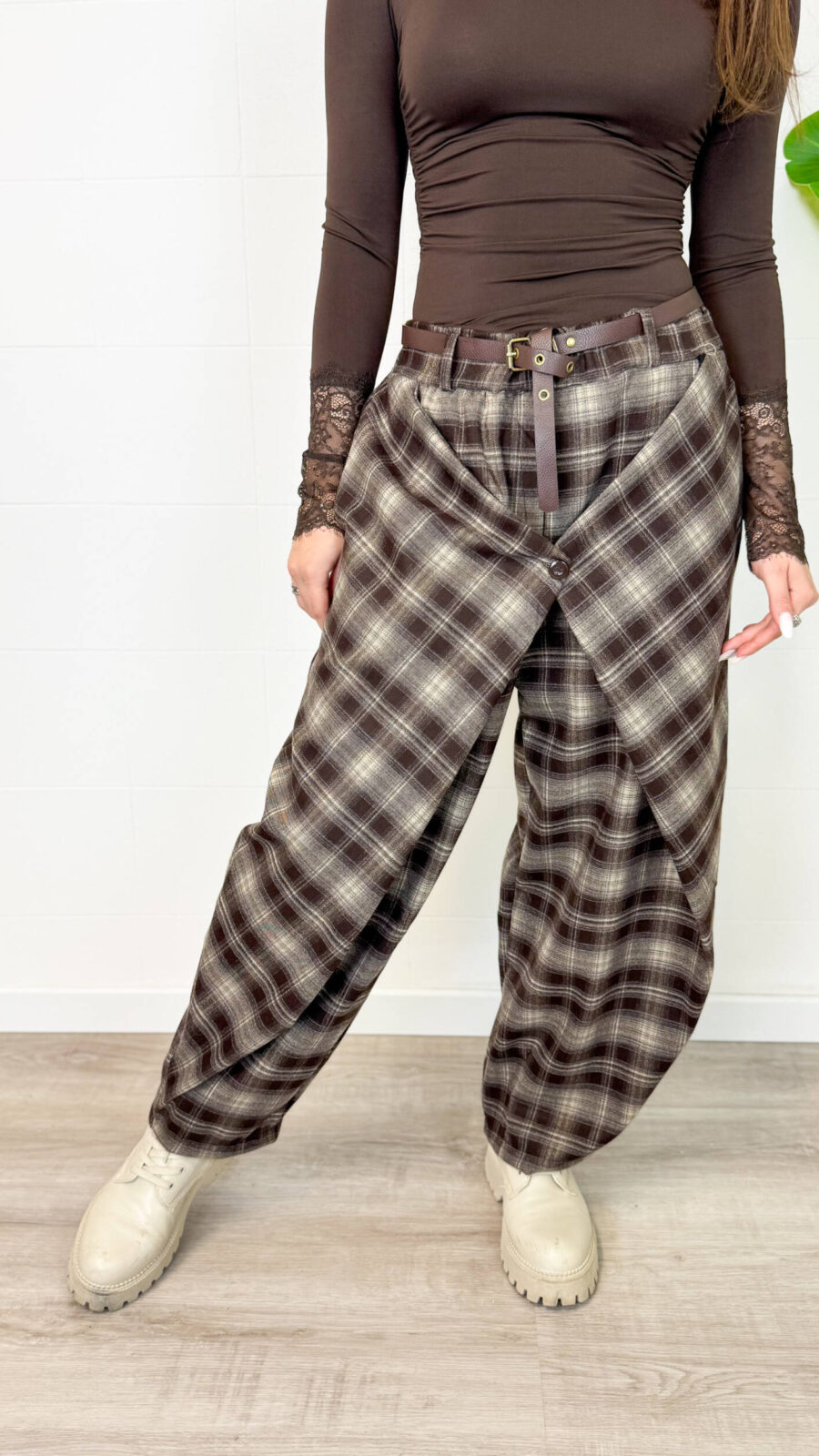 Aggiungi un tacco di stile audace e contemporaneo al tuo guardaroba con questi pantaloni cargo baggy a quadri. Caratterizzati da un motivo tartan nei toni caldi del marrone, nero e grigio, offrono il perfetto connubio tra estetica vintage Y2K, atmosfera grunge e massimo comfort quotidiano. Design e Vestibilità: Taglio ampio e morbido (baggy/balloon) con caviglie leggermente arricciate/regolabili per creare un volume moderno e rilassato. Dettagli Funzionali: Chiusura frontale con zip e bottone, passanti per cintura e pratiche tasche laterali stile cargo per un look urbano e pratico. Versatilità di Stile: Perfetti da abbinare con anfibi o sneaker spesse, top aderenti a manica lunga o maglioni oversize per un outfit da giorno grintoso ed eclettico.