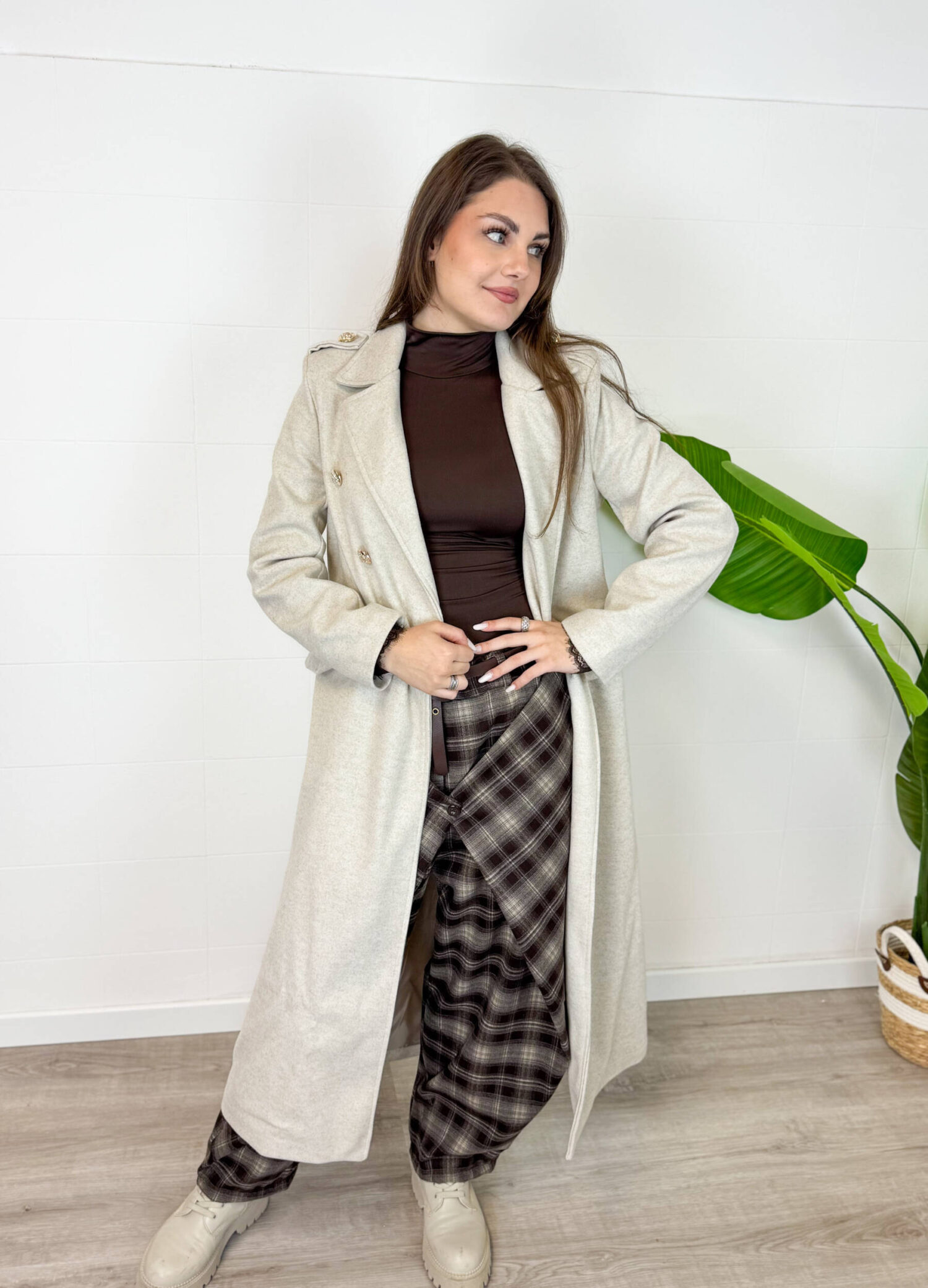 Cappotto da donna color beige dal design elegante e senza tempo. Il modello doppiopetto con revers classici e cintura in vita valorizza la silhouette e dona un tocco raffinato a ogni outfit. Perfetto da indossare nelle giornate più fresche, si abbina facilmente a jeans, pantaloni eleganti e stivali per un look chic e versatile. Un capo essenziale per un guardaroba femminile moderno e sofisticato.