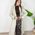 Cappotto da donna color beige dal design elegante e senza tempo. Il modello doppiopetto con revers classici e cintura in vita valorizza la silhouette e dona un tocco raffinato a ogni outfit. Perfetto da indossare nelle giornate più fresche, si abbina facilmente a jeans, pantaloni eleganti e stivali per un look chic e versatile. Un capo essenziale per un guardaroba femminile moderno e sofisticato.