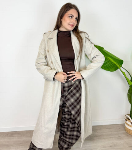 Cappotto da donna color beige dal design elegante e senza tempo. Il modello doppiopetto con revers classici e cintura in vita valorizza la silhouette e dona un tocco raffinato a ogni outfit. Perfetto da indossare nelle giornate più fresche, si abbina facilmente a jeans, pantaloni eleganti e stivali per un look chic e versatile. Un capo essenziale per un guardaroba femminile moderno e sofisticato.