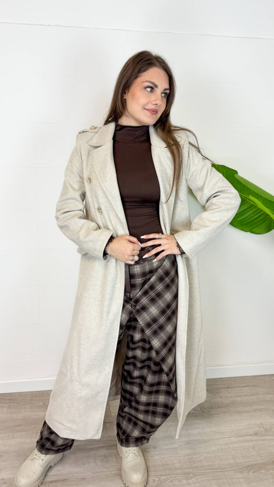 Cappotto da donna color beige dal design elegante e senza tempo. Il modello doppiopetto con revers classici e cintura in vita valorizza la silhouette e dona un tocco raffinato a ogni outfit. Perfetto da indossare nelle giornate più fresche, si abbina facilmente a jeans, pantaloni eleganti e stivali per un look chic e versatile. Un capo essenziale per un guardaroba femminile moderno e sofisticato.