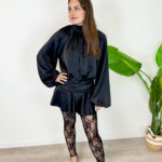 Rendi indimenticabile il tuo outfit con il nostro minidress in rasetto dal fascino sofisticato. Il tessuto satinato, morbido e luminoso, avvolge la figura donando un tocco di eleganza senza tempo. Il design frontale presenta un raffinato colletto rialzato con morbidi drappeggi e maniche lunghe blusanti con polsini stilizzati. Sul retro, il vestito svela un dettaglio inaspettato e sensuale: un'apertura a goccia sulla schiena che si allaccia dietro al collo con delicati bottoncini. Ma il vero segreto di questo abito è la comodità: sotto la minigonna a portafoglio si cela un pantaloncino interno coordinato, studiato per permetterti di ballare, muoverti e vivere la serata in totale disinvoltura e senza pensieri.