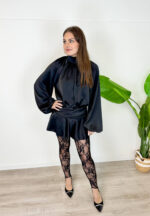 Rendi indimenticabile il tuo outfit con il nostro minidress in rasetto dal fascino sofisticato. Il tessuto satinato, morbido e luminoso, avvolge la figura donando un tocco di eleganza senza tempo. Il design frontale presenta un raffinato colletto rialzato con morbidi drappeggi e maniche lunghe blusanti con polsini stilizzati. Sul retro, il vestito svela un dettaglio inaspettato e sensuale: un'apertura a goccia sulla schiena che si allaccia dietro al collo con delicati bottoncini. Ma il vero segreto di questo abito è la comodità: sotto la minigonna a portafoglio si cela un pantaloncino interno coordinato, studiato per permetterti di ballare, muoverti e vivere la serata in totale disinvoltura e senza pensieri.