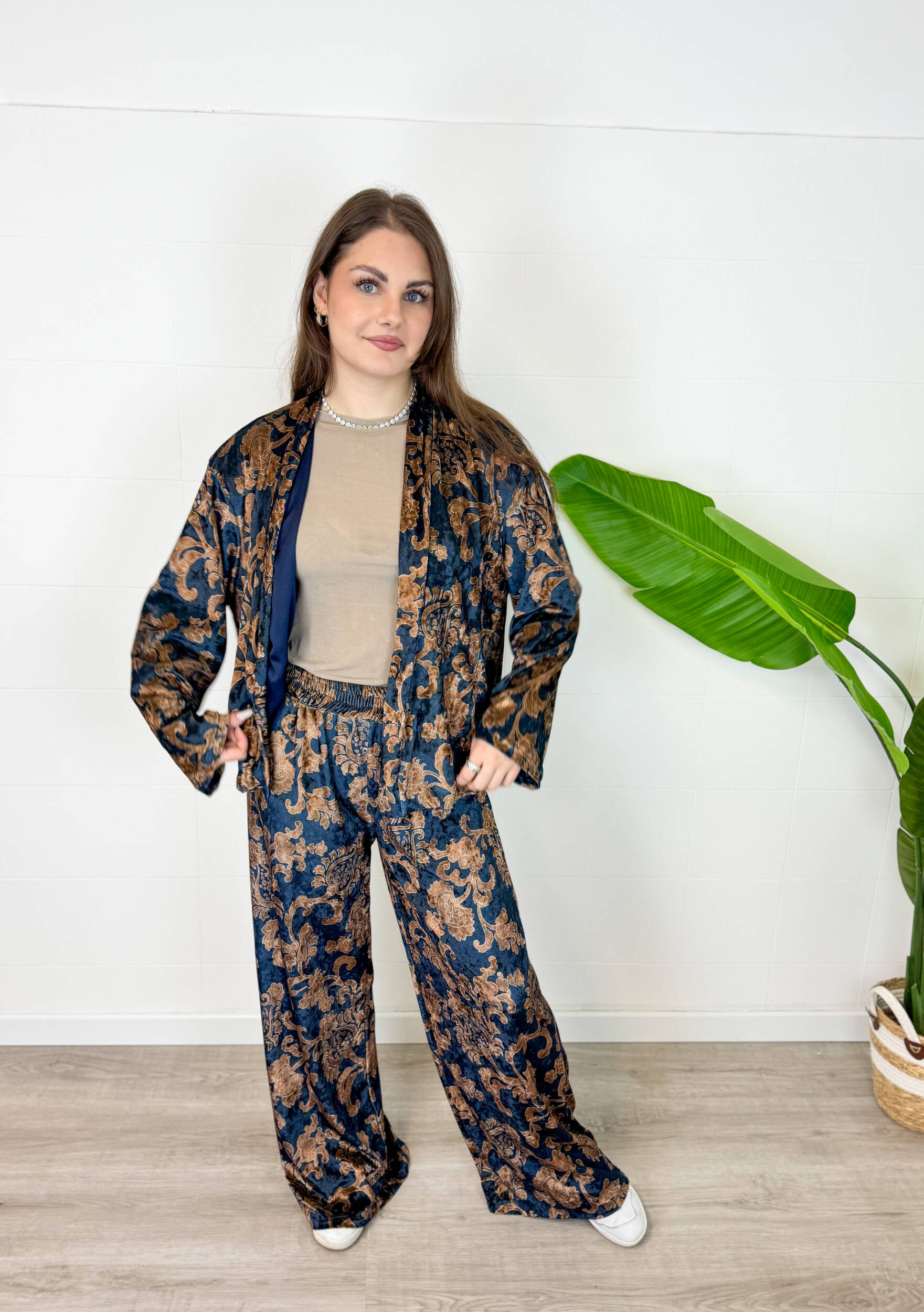 IMG_1332 Eleganza lussuosa e massimo comfort si incontrano in questo coordinato due pezzi effetto velluto. Caratterizzato da una raffinata giacca taglio stile kimono aperta sul davanti e pantalone palazzo a gamba larga, questo completino è impreziosito da un'elegante fantasia floreale/barocca su fondo blu scuro e tonalità bronzee. La rifinitura interna in morbido rasetto garantisce una sensazione di estrema piacevolezza e fluidità sulla pelle.